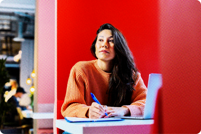 Business woman thinking holding a pen in front of a laptop