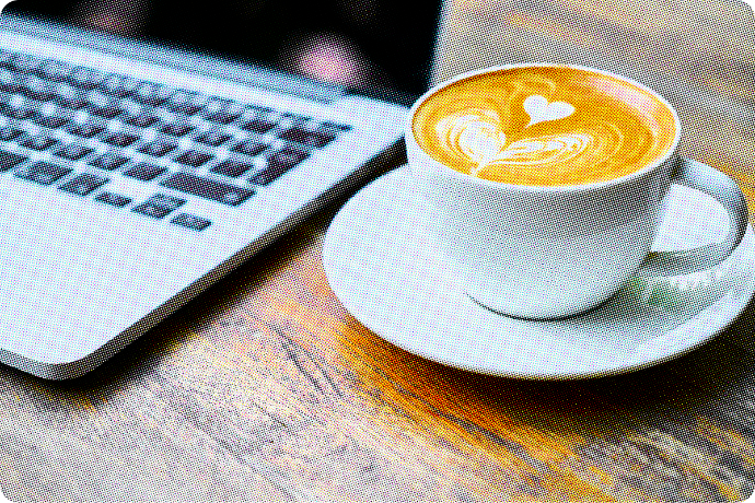 A cup of coffee sits next to a laptop.