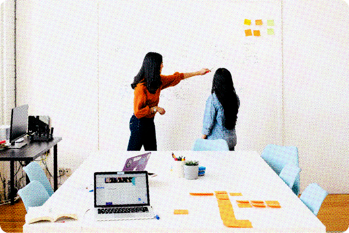Two women plan their project on a white board. 