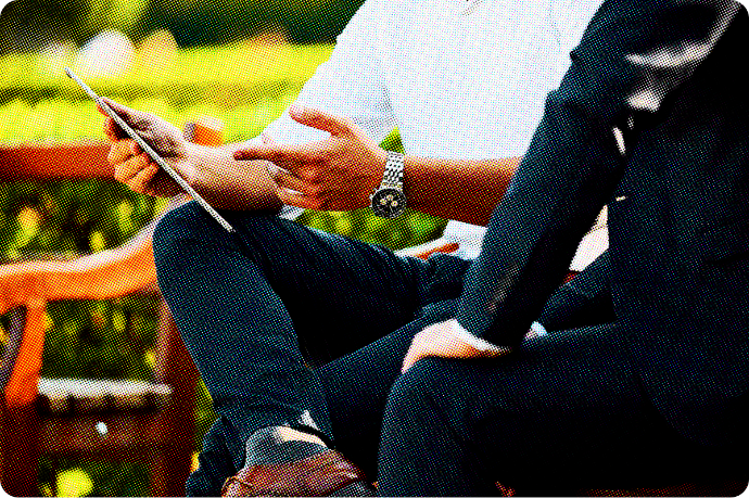 Man holding a tablet while sitting on a bench. 