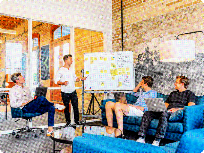 Image of a marketing team sitting around a whiteboard and creating a marketing campaign