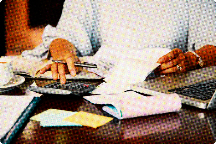 Image showing a male professional looking through a pile of paperwork and receipts while using a calculator to calculate them.